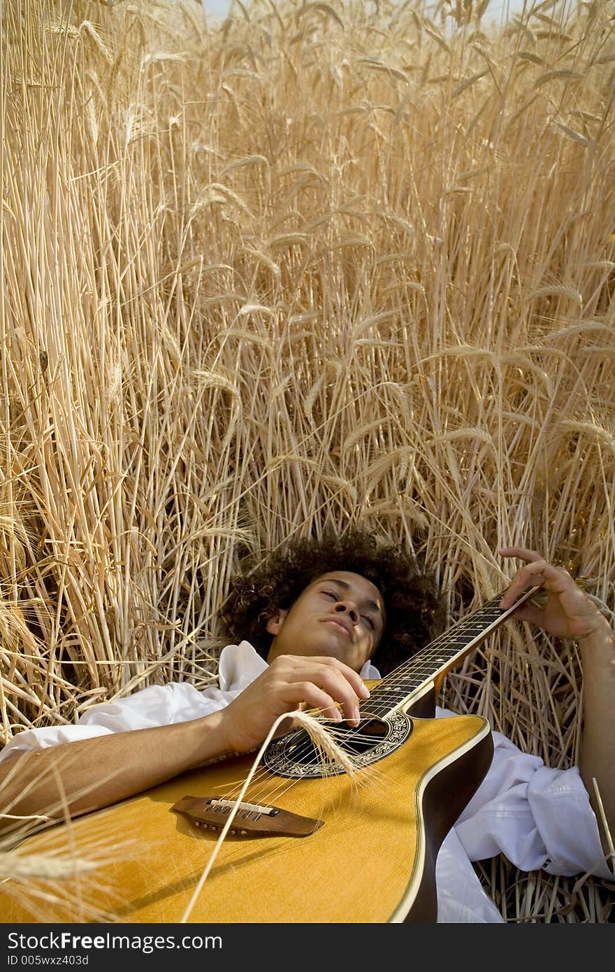 Cool guy laying in a cornfield playing guitar. Cool guy laying in a cornfield playing guitar