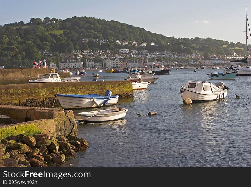 Boats moored in harbour with coastal village in background. Boats moored in harbour with coastal village in background