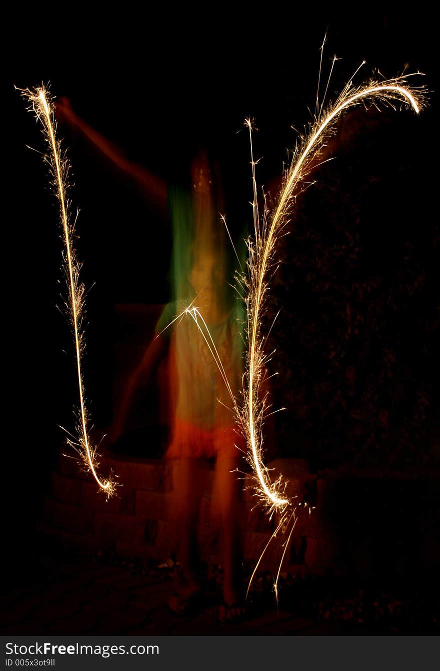 Long exsopure blurred action of child jumping up and down wile holding sparklers in her hands. Long exsopure blurred action of child jumping up and down wile holding sparklers in her hands.