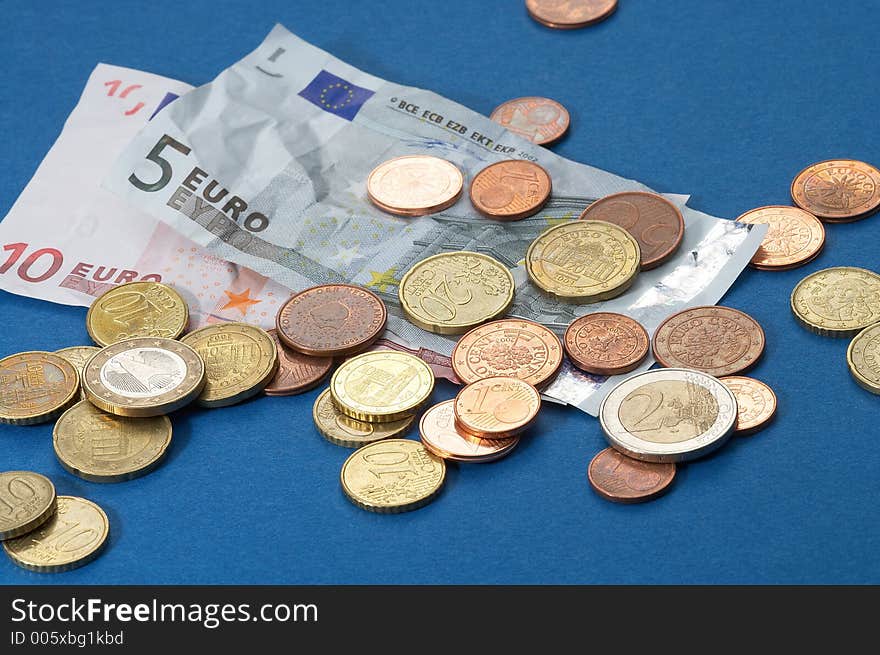 Paper money and different coins on blue background. Paper money and different coins on blue background