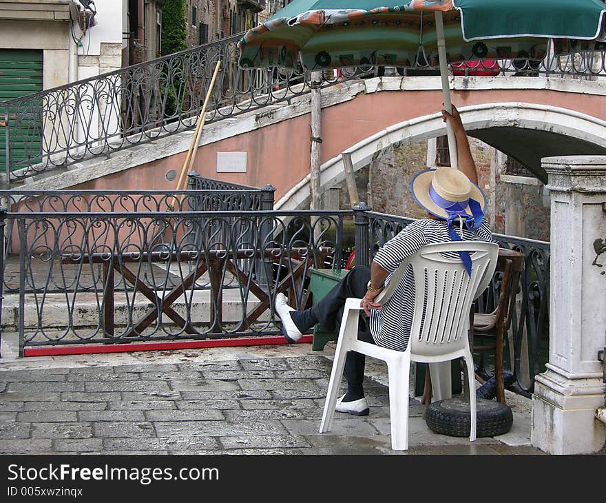 A venetian gondolier sitting and waiting for tourists. A venetian gondolier sitting and waiting for tourists