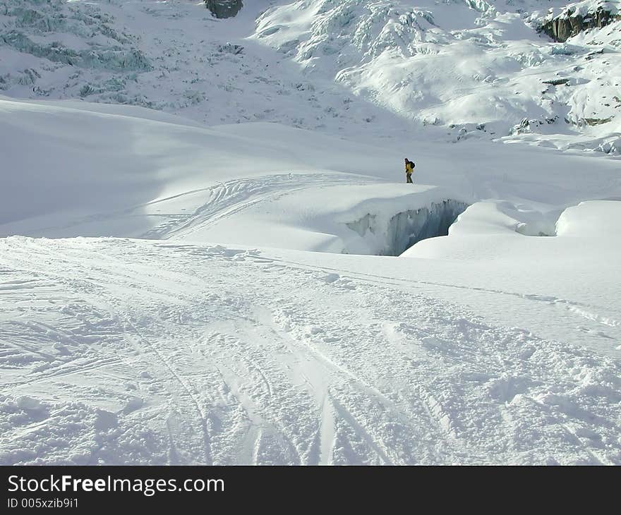 Snowboader crossing snow bridge. Snowboader crossing snow bridge