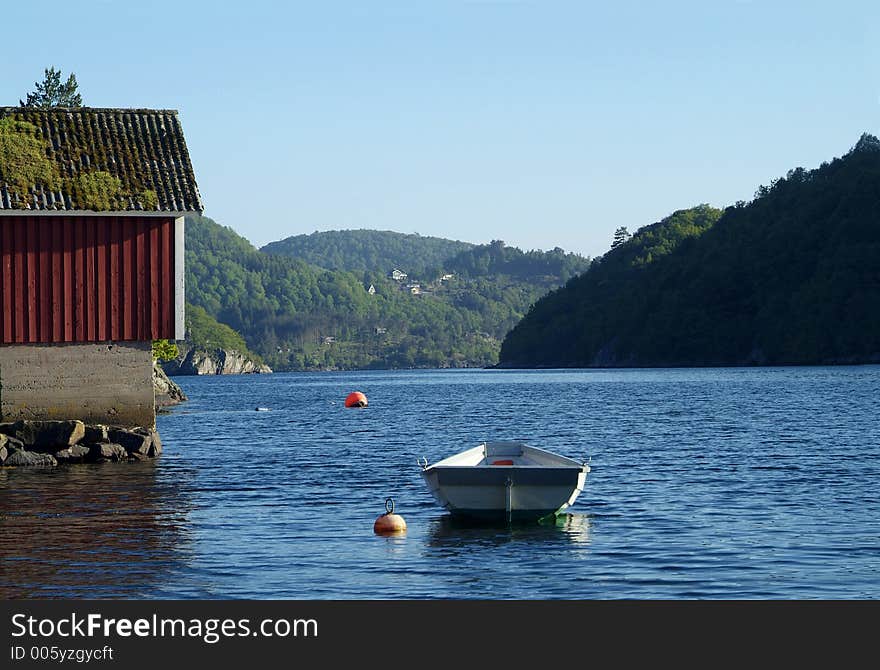 Traditional dinghy and old boathouse in a fjord on the Norwegian south coast