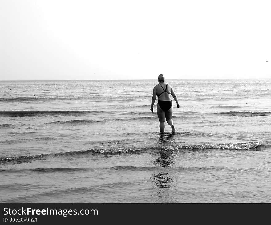 Female paddler wading into the sea. Female paddler wading into the sea