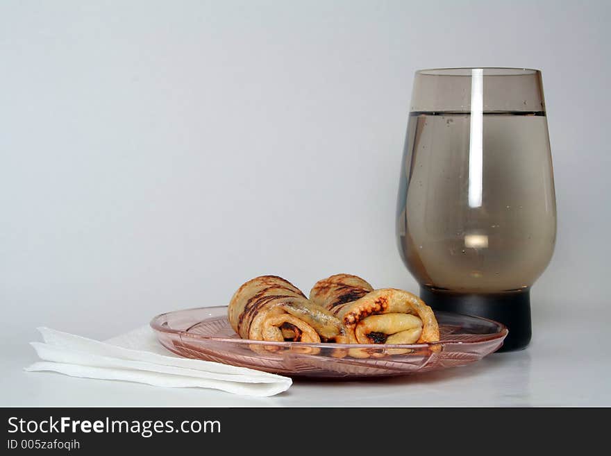 Rolled pancakes with strawberry jam and a glass of water