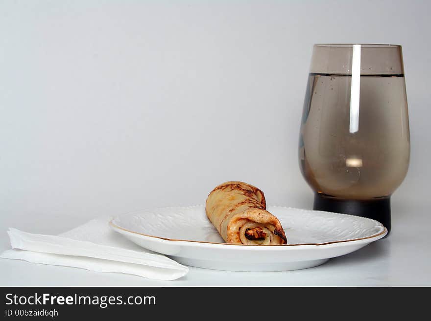 Rolled pancake with sweet strawberry jam and glass of fresh mineral cool water. Rolled pancake with sweet strawberry jam and glass of fresh mineral cool water