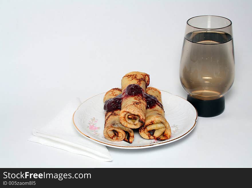 Rolled pancakes with strawberry jam and a glass of water