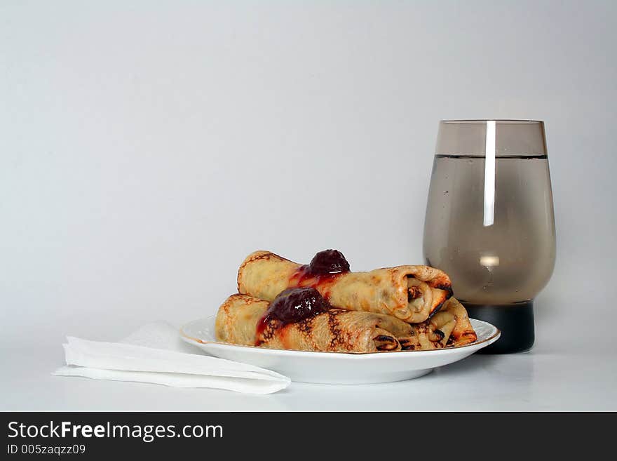 Rolled pancakes with strawberry jam and a glass of water