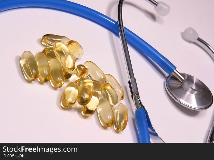 Gold jell caps and blue stethoscope. Gold jell caps and blue stethoscope.