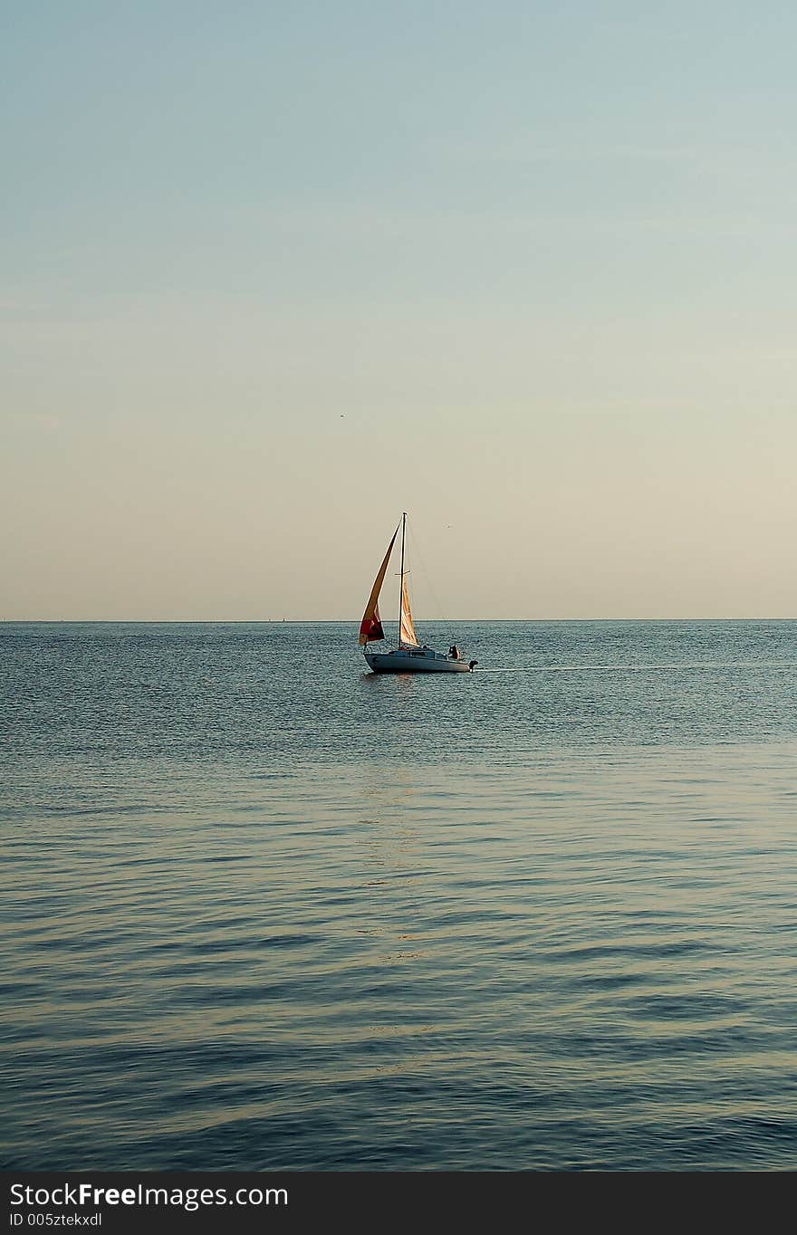 Sailboat sailing on the sea or ocean under the clear sky just before the sunset