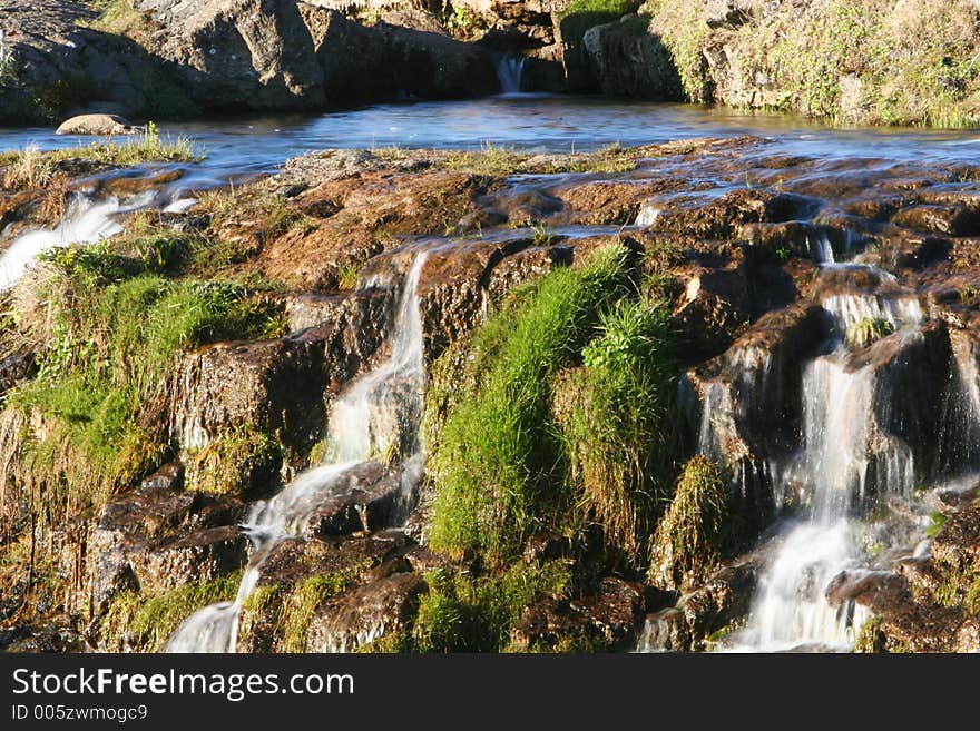 Photograph of small river, flowing, waterfalls, lush green vegetation and genuine tranquil athmosphere. Photograph of small river, flowing, waterfalls, lush green vegetation and genuine tranquil athmosphere