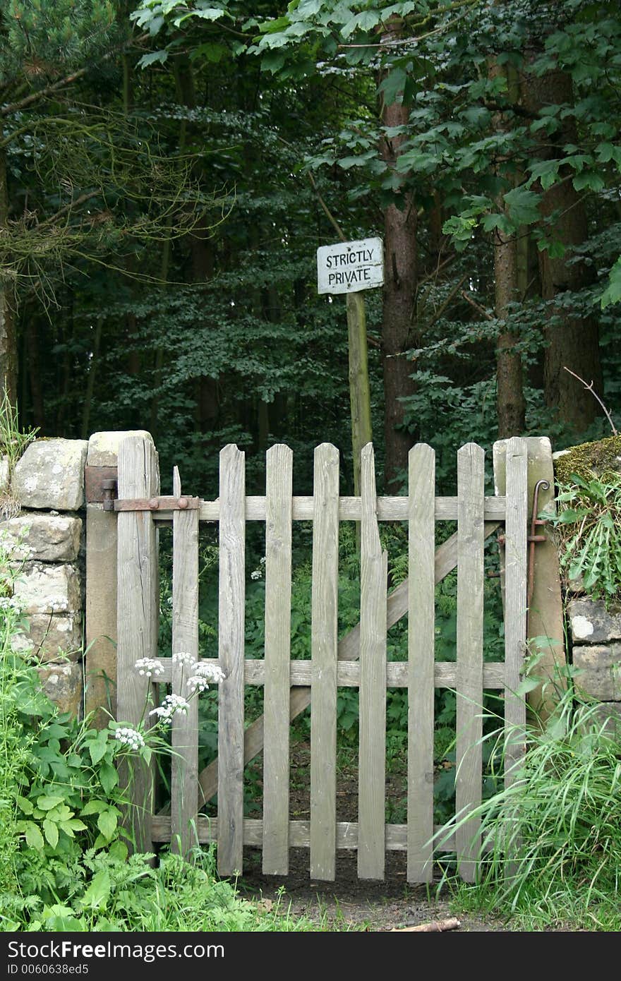 Old broken wooden gate leads to a path thorough the wood but the sign stictly private wards off any unwelcome person. Old broken wooden gate leads to a path thorough the wood but the sign stictly private wards off any unwelcome person