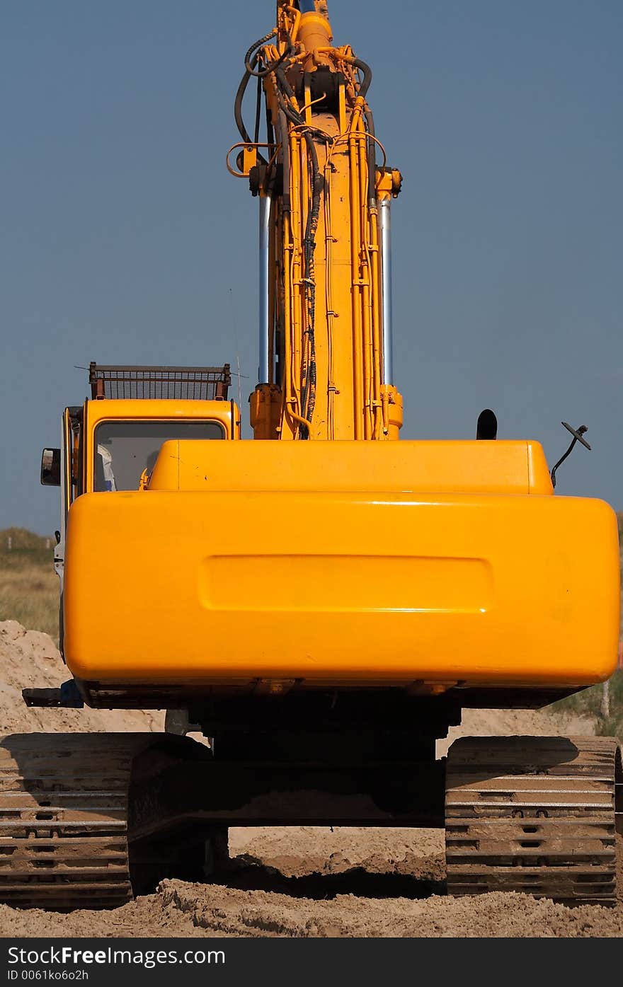 Backside of orange digger on blue background sky. Backside of orange digger on blue background sky.