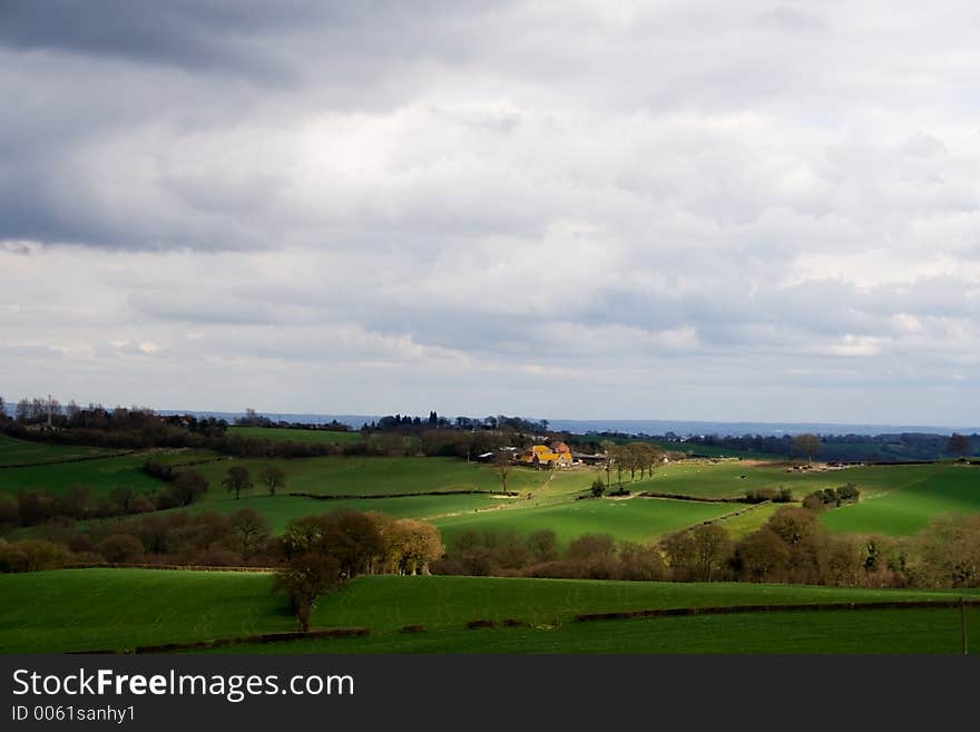 View across farmland to house illuminated by the sun. View across farmland to house illuminated by the sun