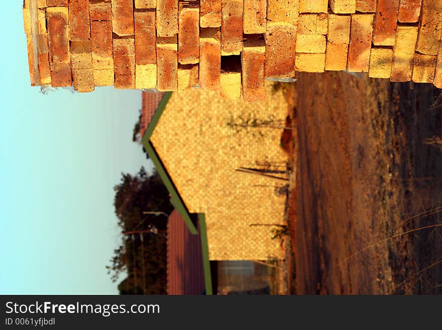 Close up of a pile of brinks on a building site, with completed home in the background