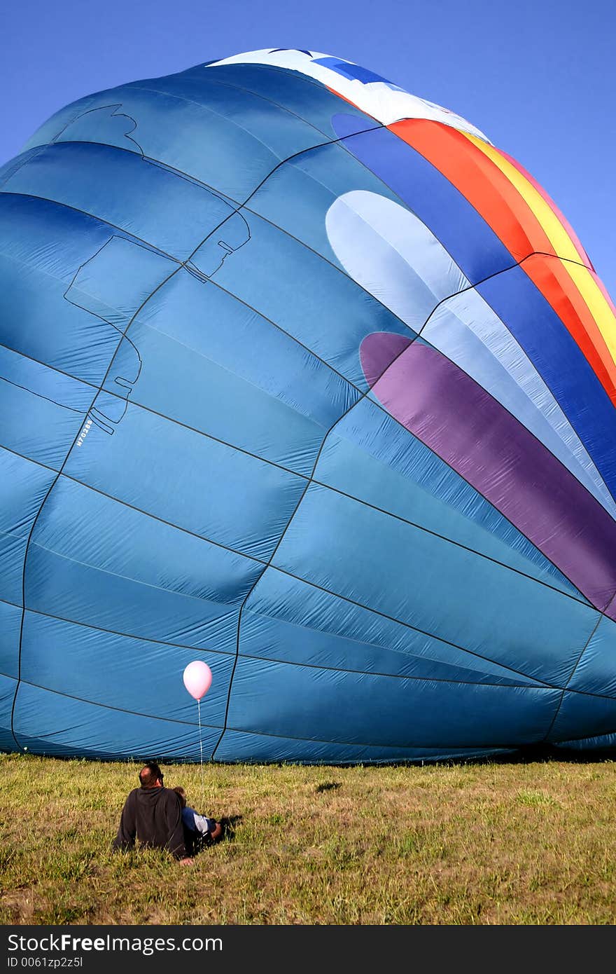 Colorful Hot Air Balloon on Ground with Father and Daughter sitting and Watching