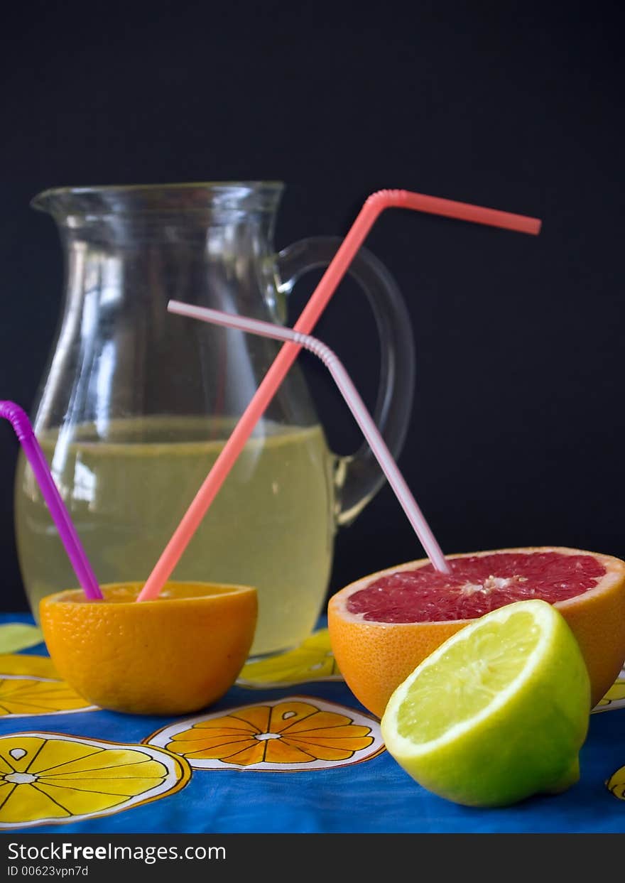 Fresh fruits and lemonade at jug, black background