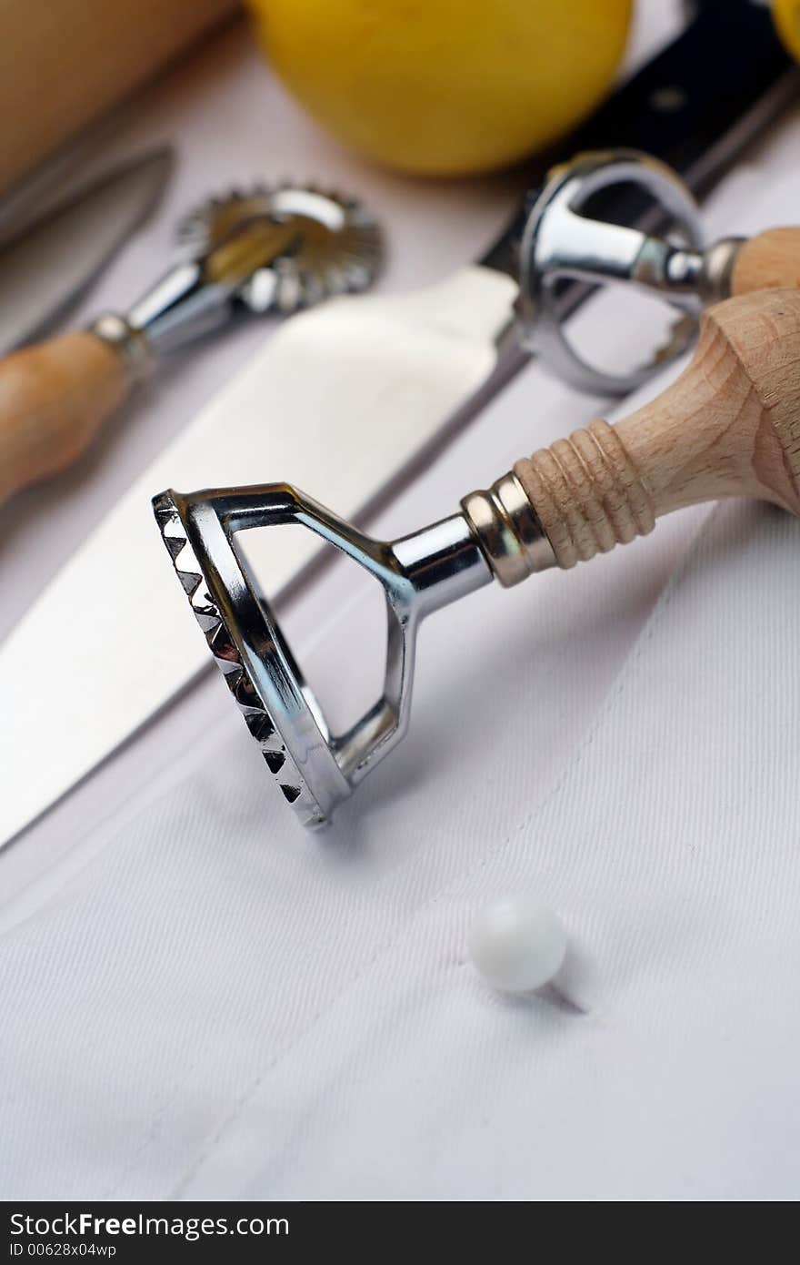 An assembly of chef's tools of trade sitting on a new chef's uniform. a couple of lemons in the background. An assembly of chef's tools of trade sitting on a new chef's uniform. a couple of lemons in the background.