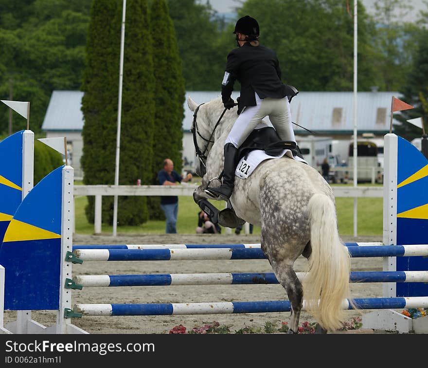 Horse and rider powering up and over hurdle