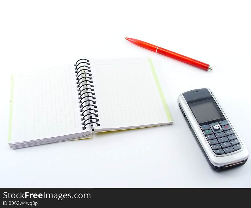 Notebook with cell phone and red pen on white table