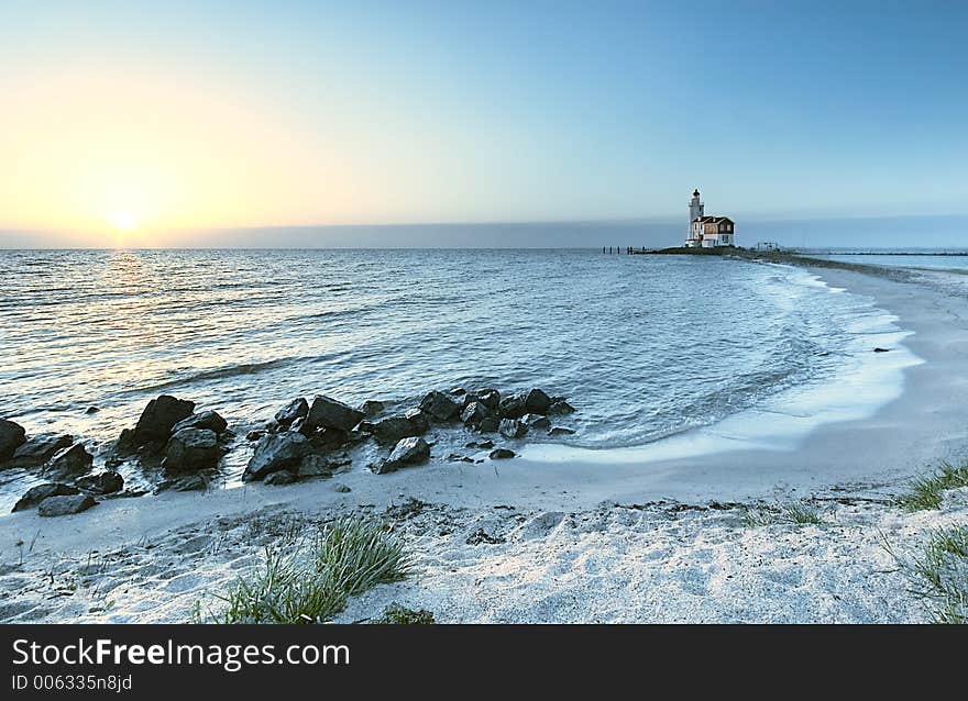 A beautiful beach and lighthouse at sunrise. A beautiful beach and lighthouse at sunrise