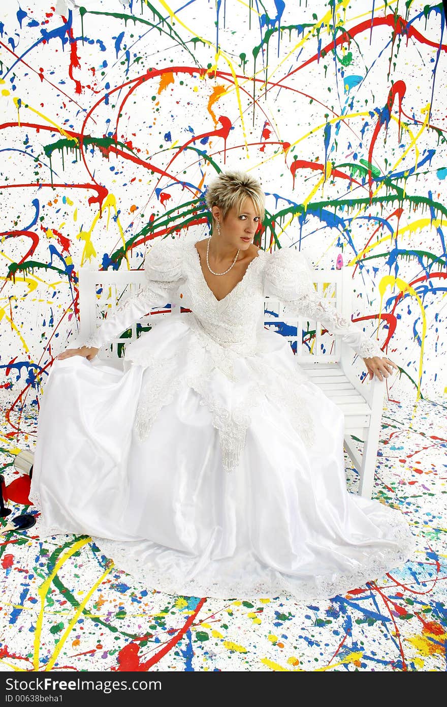 Beautiful young woman in bridal gown sitting on bench; splattered paint background. Beautiful young woman in bridal gown sitting on bench; splattered paint background