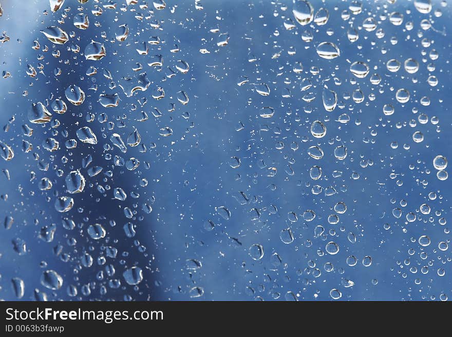 Raindrops at a window - blue background. Raindrops at a window - blue background