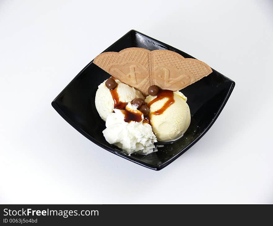 A vanilla icecream dessert with chocolate syrup and a wafer