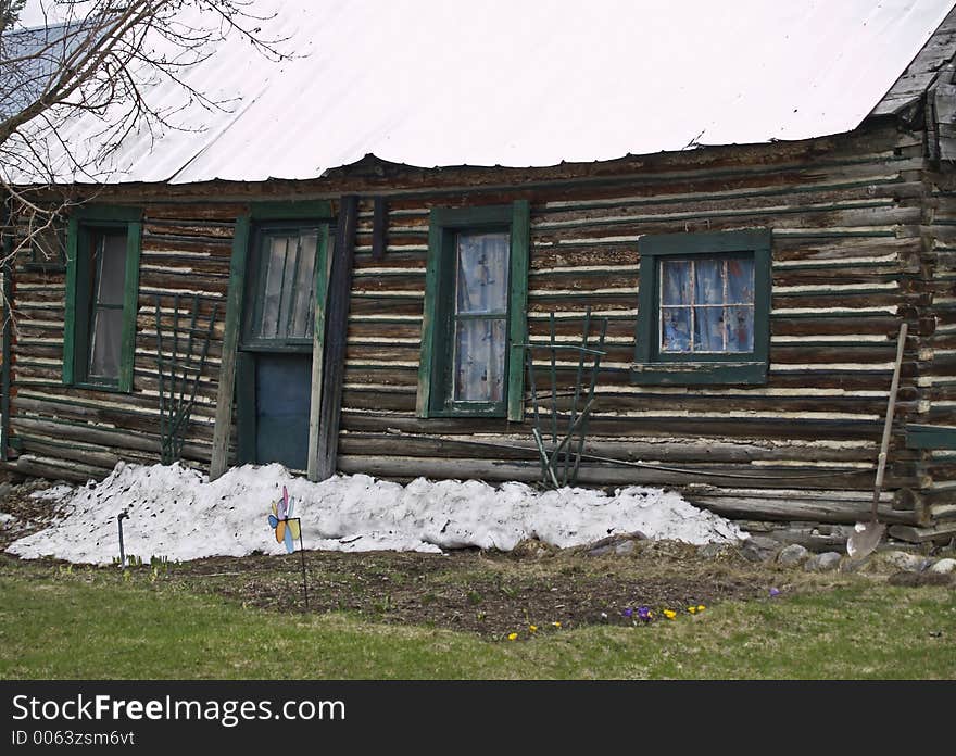 This image of the old house with the sagging roof, shovel, snow, and flowers was taken in western MT. This image of the old house with the sagging roof, shovel, snow, and flowers was taken in western MT.