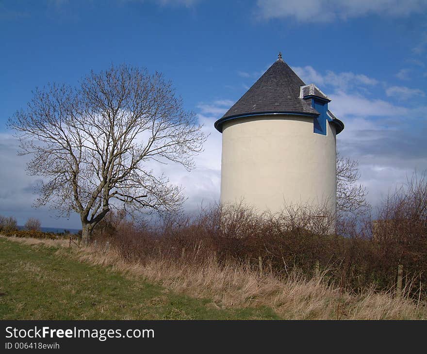 Wter tower standing beside a bare tree.
looks very similar to dovecote. Blue sky with white clouds in background. Wter tower standing beside a bare tree.
looks very similar to dovecote. Blue sky with white clouds in background.