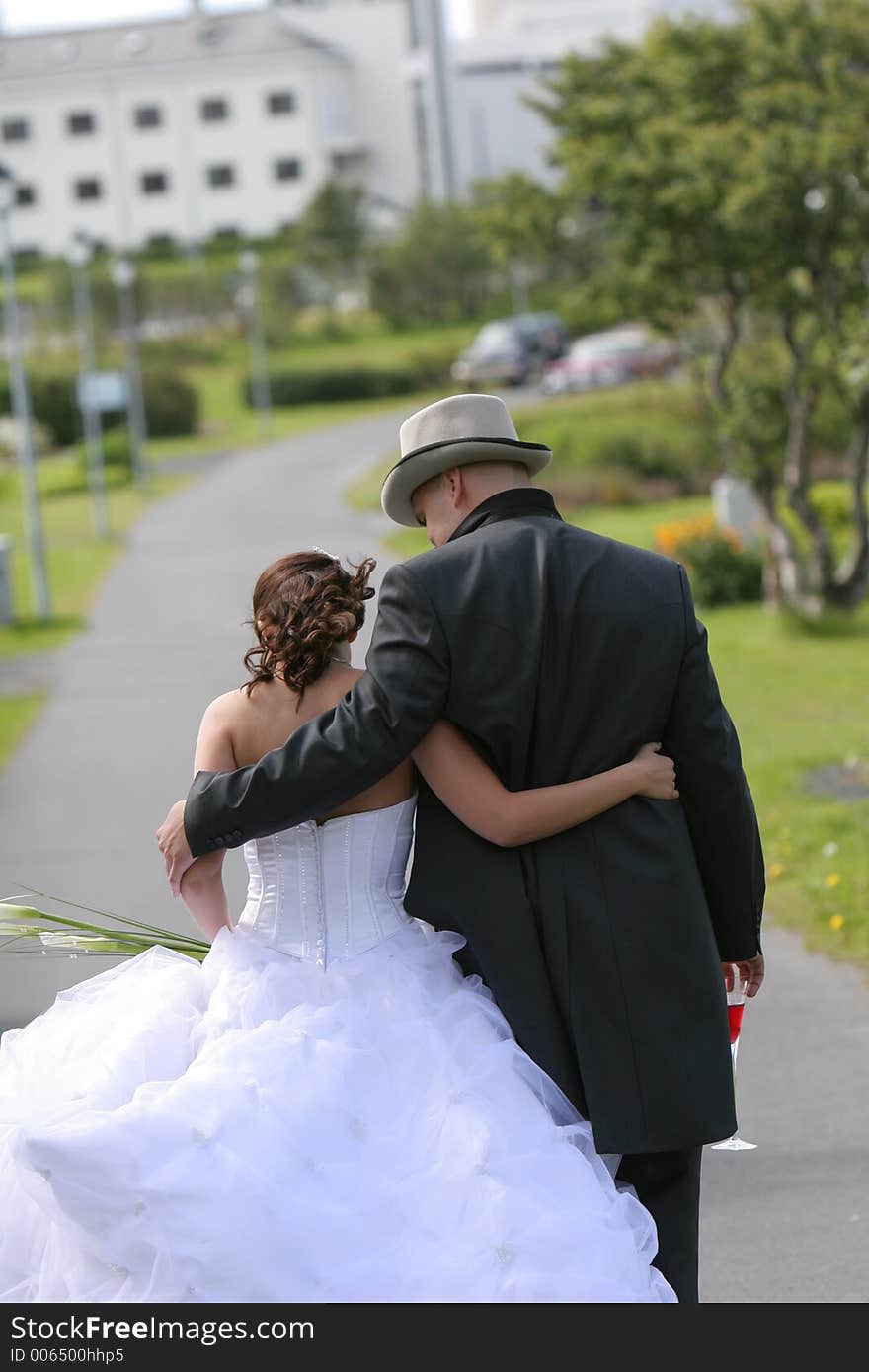 Young newlywed couple holding eachother as they walk away from camera. Young newlywed couple holding eachother as they walk away from camera