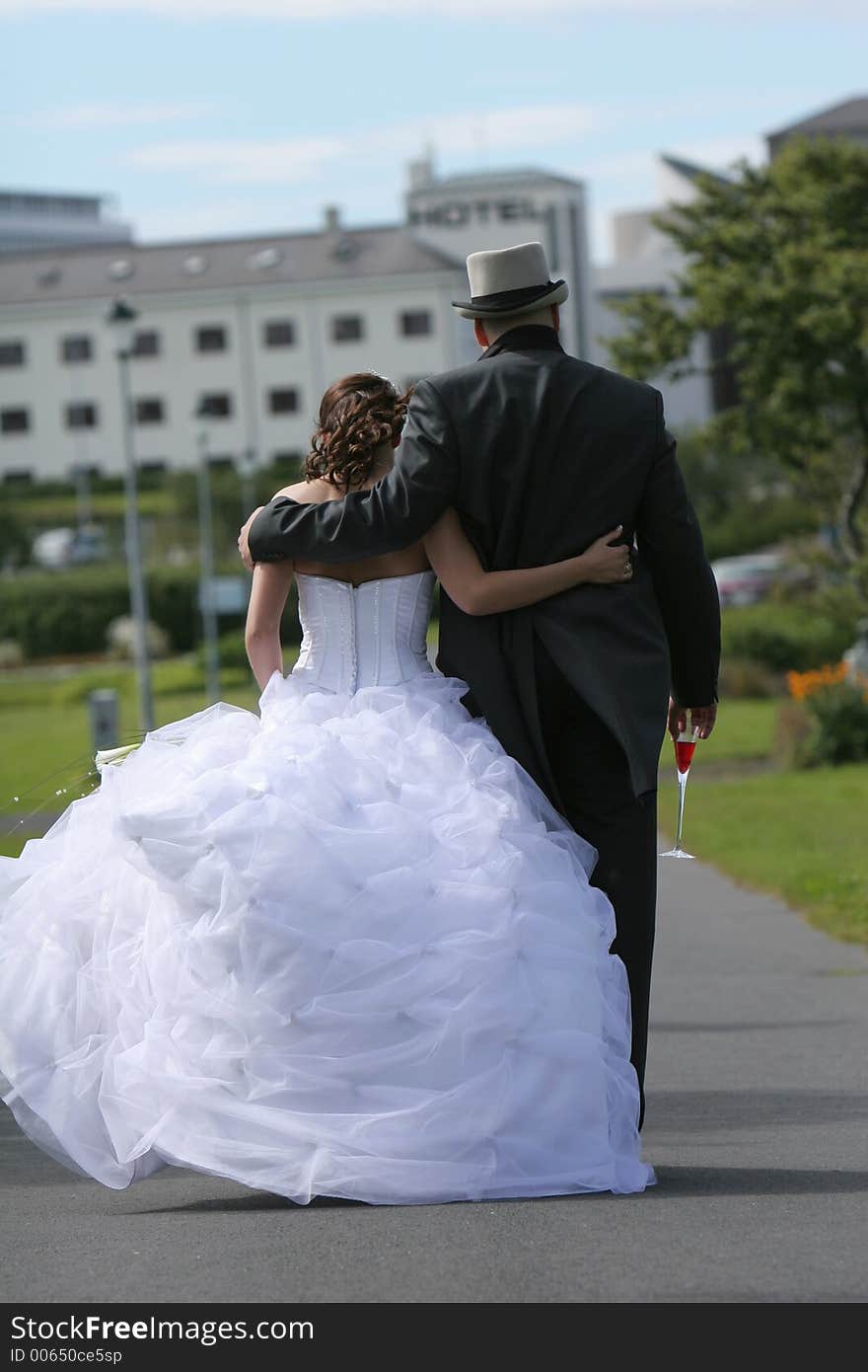 Newlyweds walking along a path, on a leisurly stroll in fantastic sunny weather. Newlyweds walking along a path, on a leisurly stroll in fantastic sunny weather