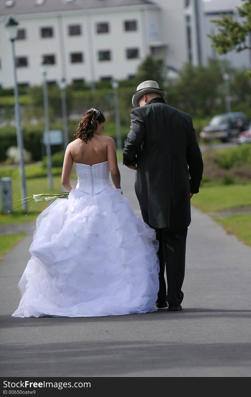 A wedding, bride and groom walking leisurely away from camera. A wedding, bride and groom walking leisurely away from camera