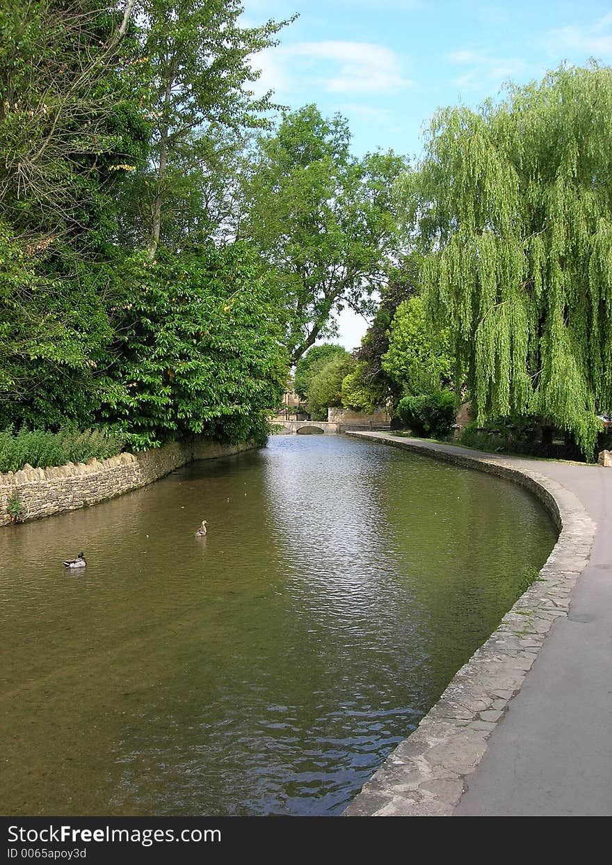 River and path leading to bridge into cotswold village