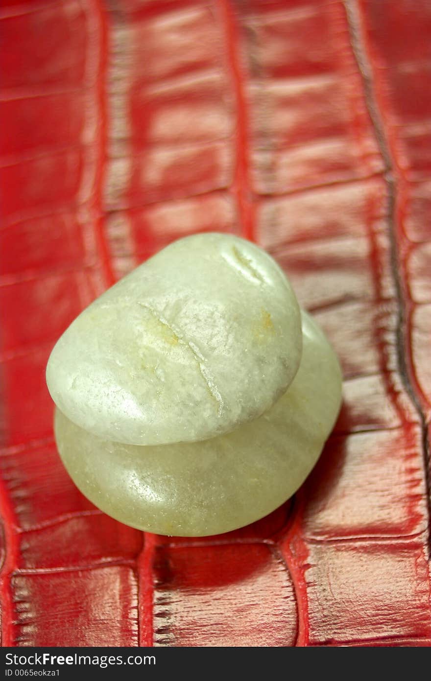 Two pebbles on red leather background. Two pebbles on red leather background