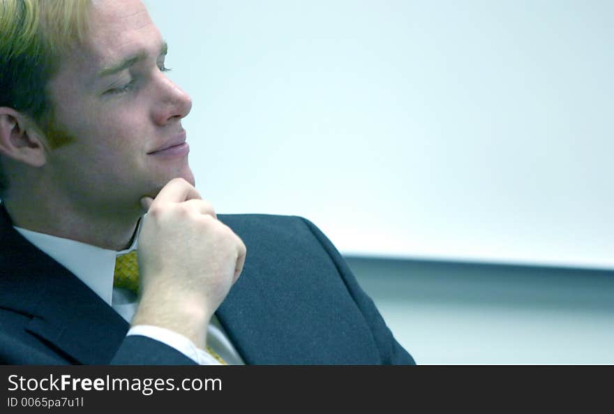 Blond hair blue eye businessman holds hand up next to his chin and smiles. Blond hair blue eye businessman holds hand up next to his chin and smiles