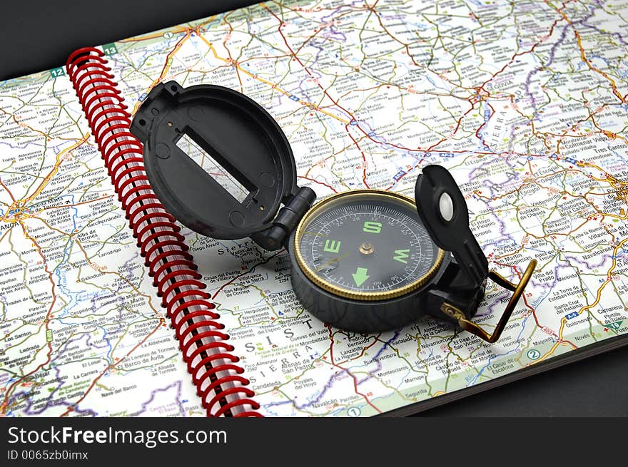 A compass is open upon a road map. A compass is open upon a road map