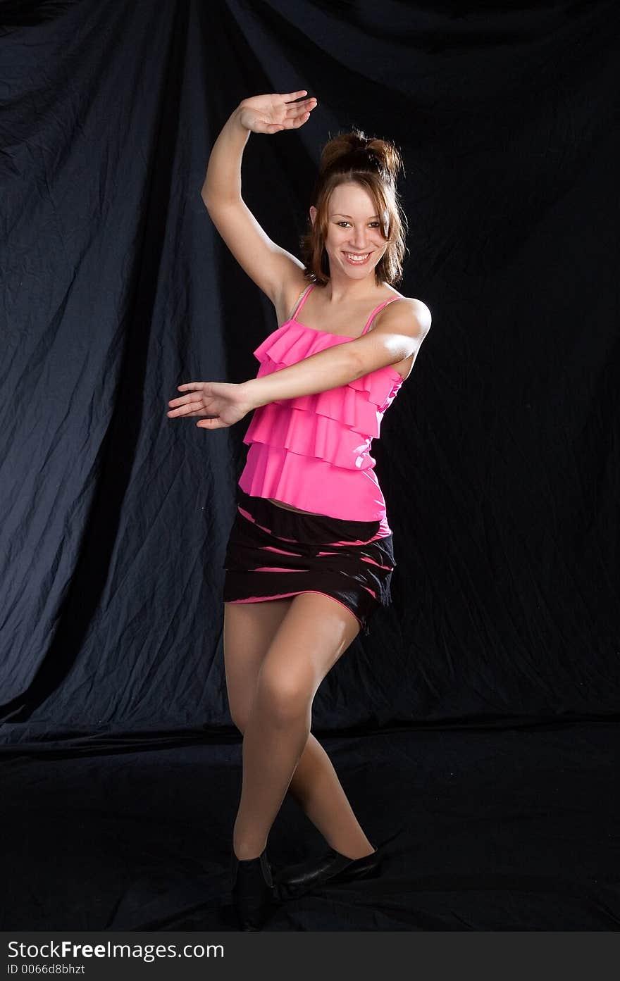 A jazz dancer posed standing in a pink costume. A jazz dancer posed standing in a pink costume