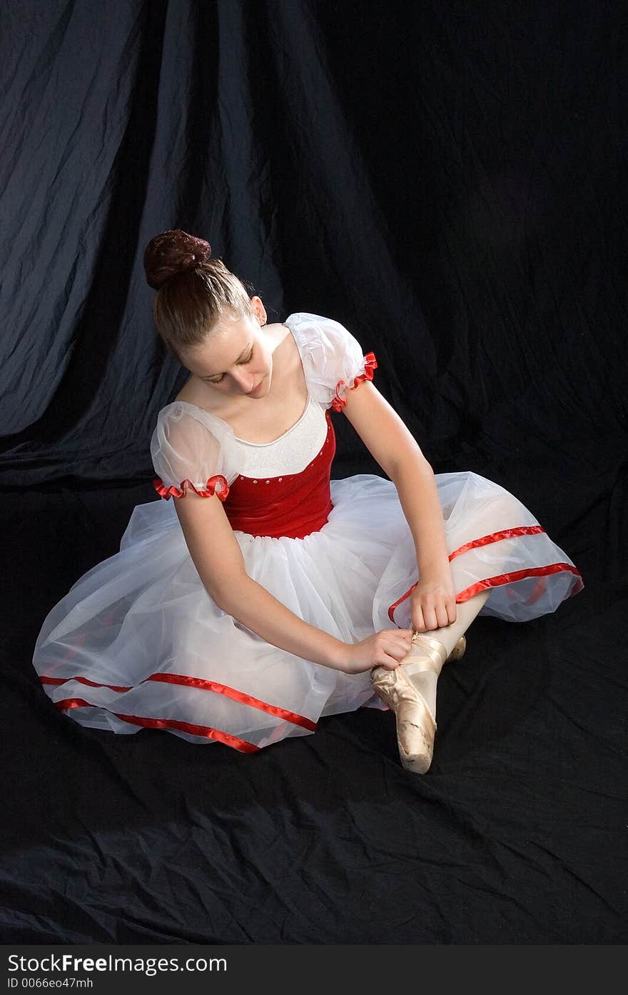 A ballerina ties her shoe ribbons to her pointe shoes. A ballerina ties her shoe ribbons to her pointe shoes