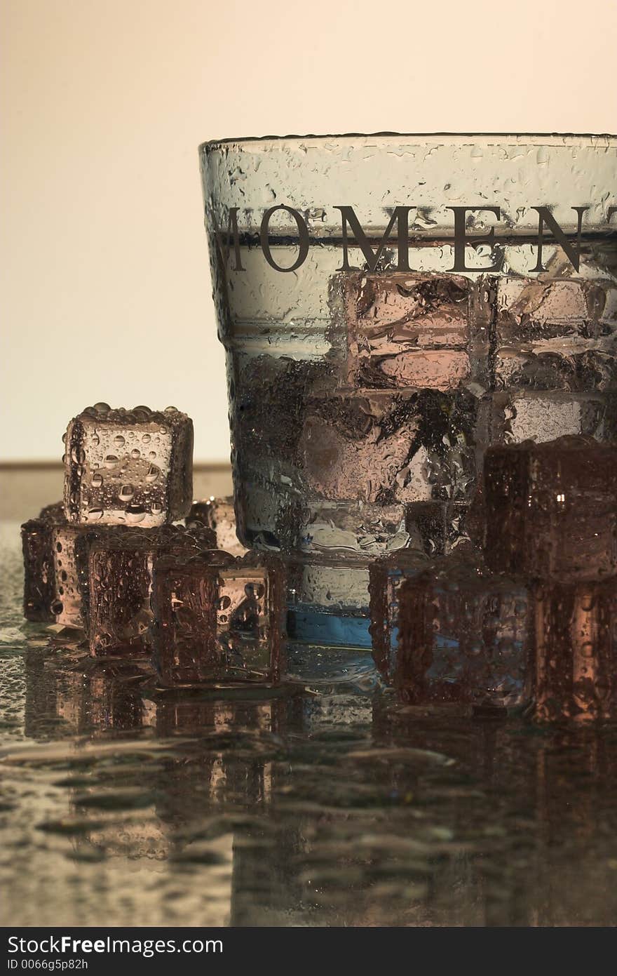 Light blue glass with ice cubes on a reflective surface