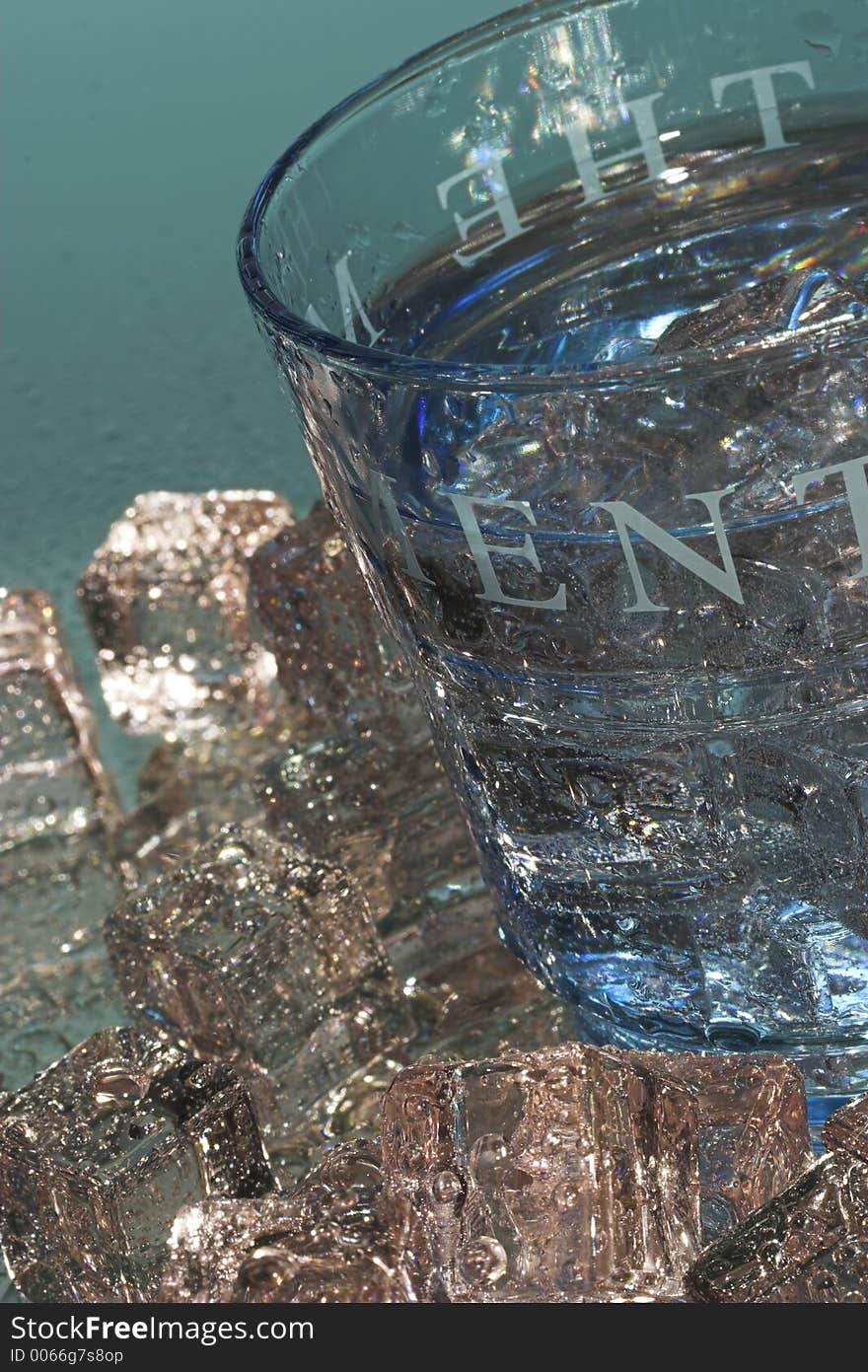 Light blue glass with ice cubes on a reflective surface