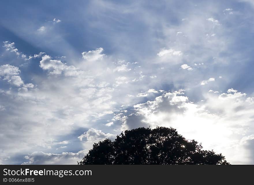 Sun rays coming off clouds in a beautiful blue sky.