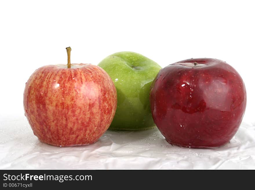 Three wet apples; one red, one green, one speckled red with water droplets on them. Three wet apples; one red, one green, one speckled red with water droplets on them.