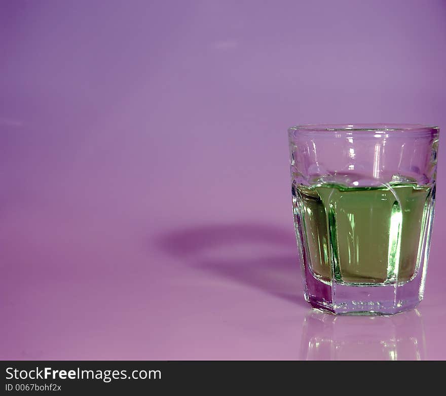 A shot glass filled with liquor and ready to shoot with a contrasty background. A shot glass filled with liquor and ready to shoot with a contrasty background.