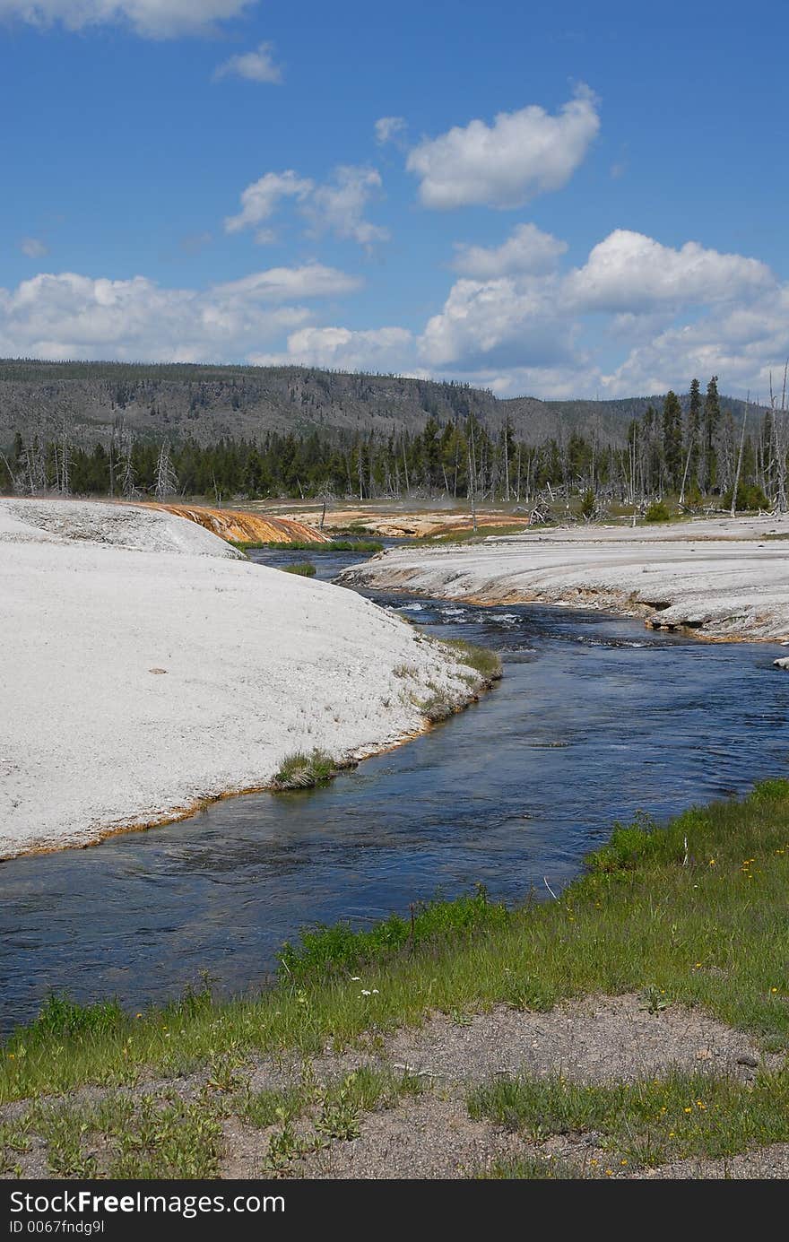 Yellowstone river flowing through the white rock formations by the mountains at the Yellowstone Natl. Park