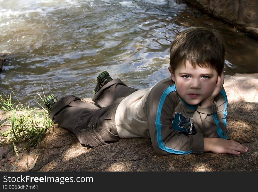 Boy posing for shot next to stream. Boy posing for shot next to stream