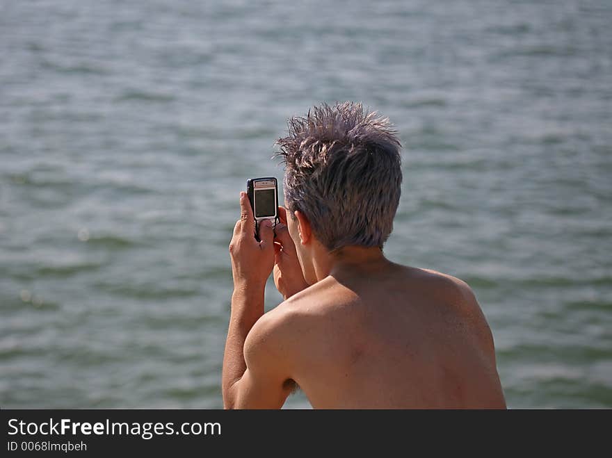 Man with cell phone looking the sea