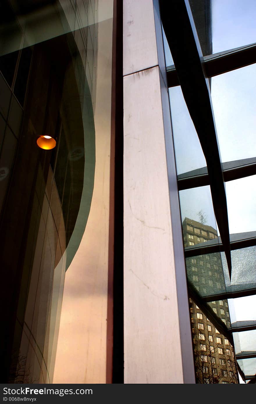 Detail of building, downtown Vancouver. Lamp shows in dark at left, claw shape under glass at right. Single building in background at right. Detail of building, downtown Vancouver. Lamp shows in dark at left, claw shape under glass at right. Single building in background at right.