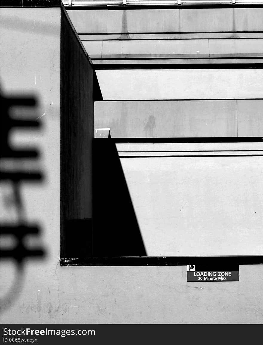 Abstract black & white scene - geometric shapes, loading zone sign at right, telephone pole shadow on left