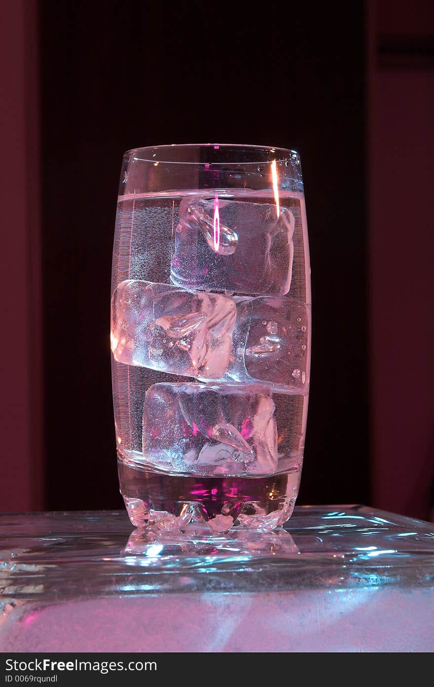 Glass of water with ice lit by purple light